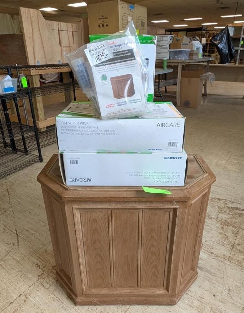 Boxes and a bag of supplies stacked on a wooden cabinet in a store aisle.