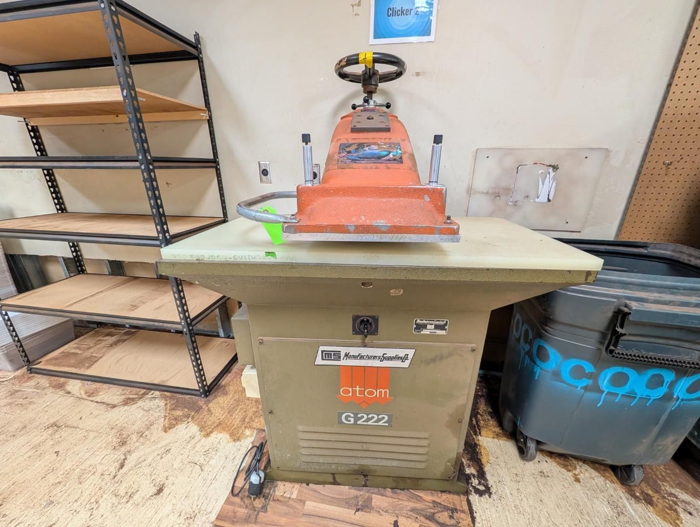 Workshop with orange machine on green cabinet, shelving on left, and bins on the right.