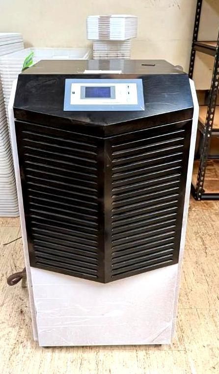Portable air conditioner with digital display, black front vents, and white base in a room