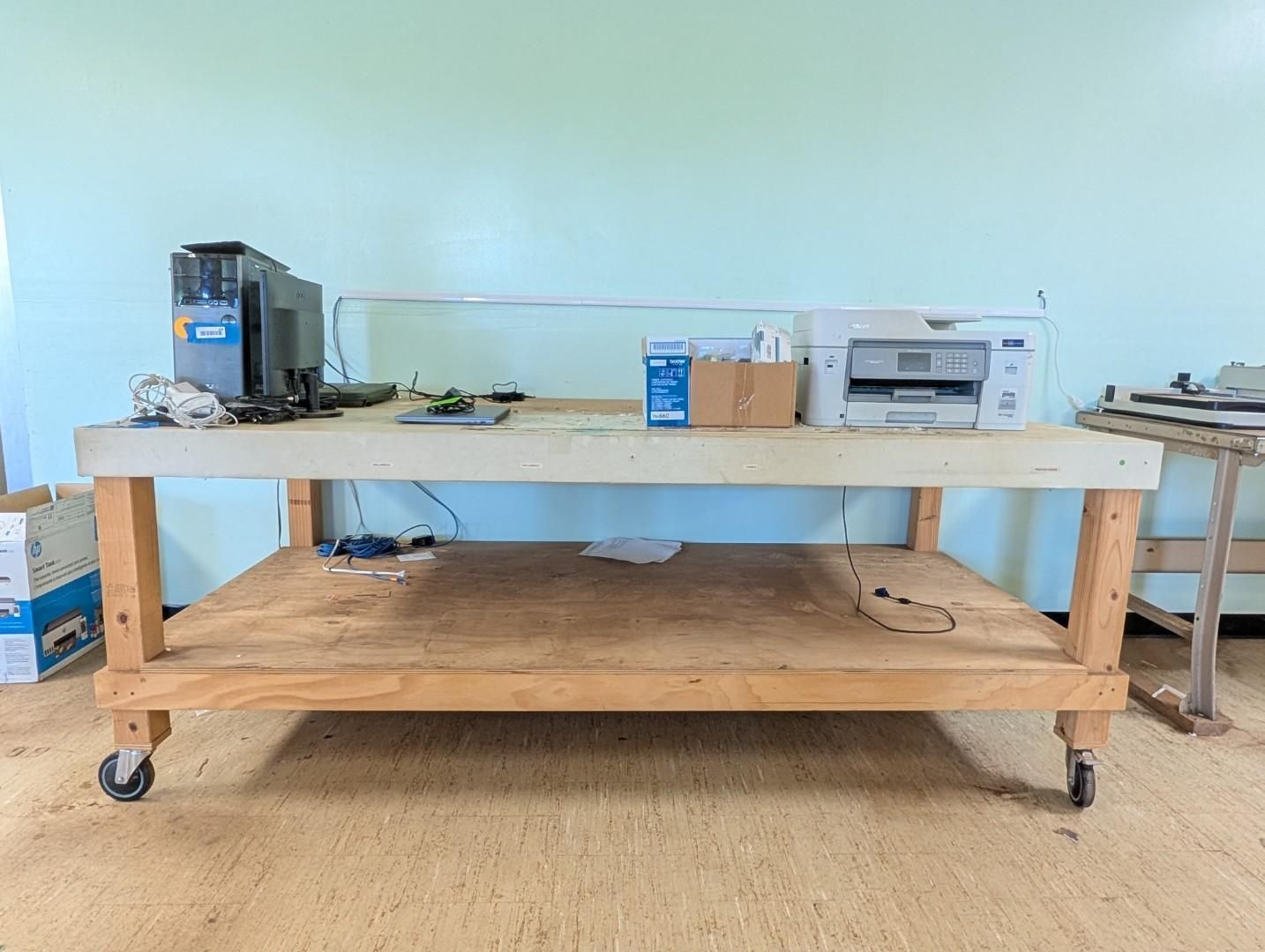 Wooden workbench with tools and equipment in a workshop, on casters against a light blue wall