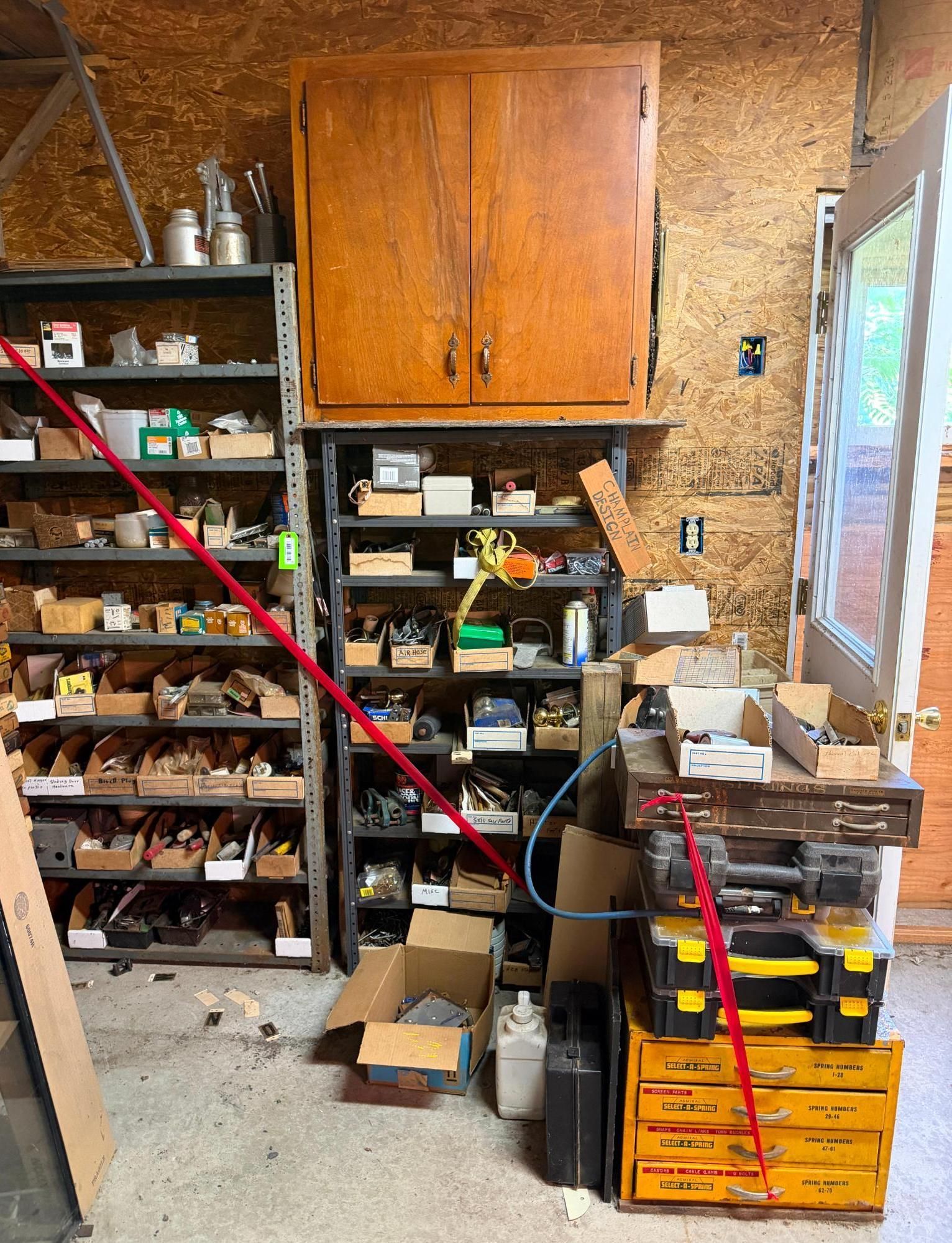 garage workshop with shelves of tools, boxes, and a large wooden cabinet.
