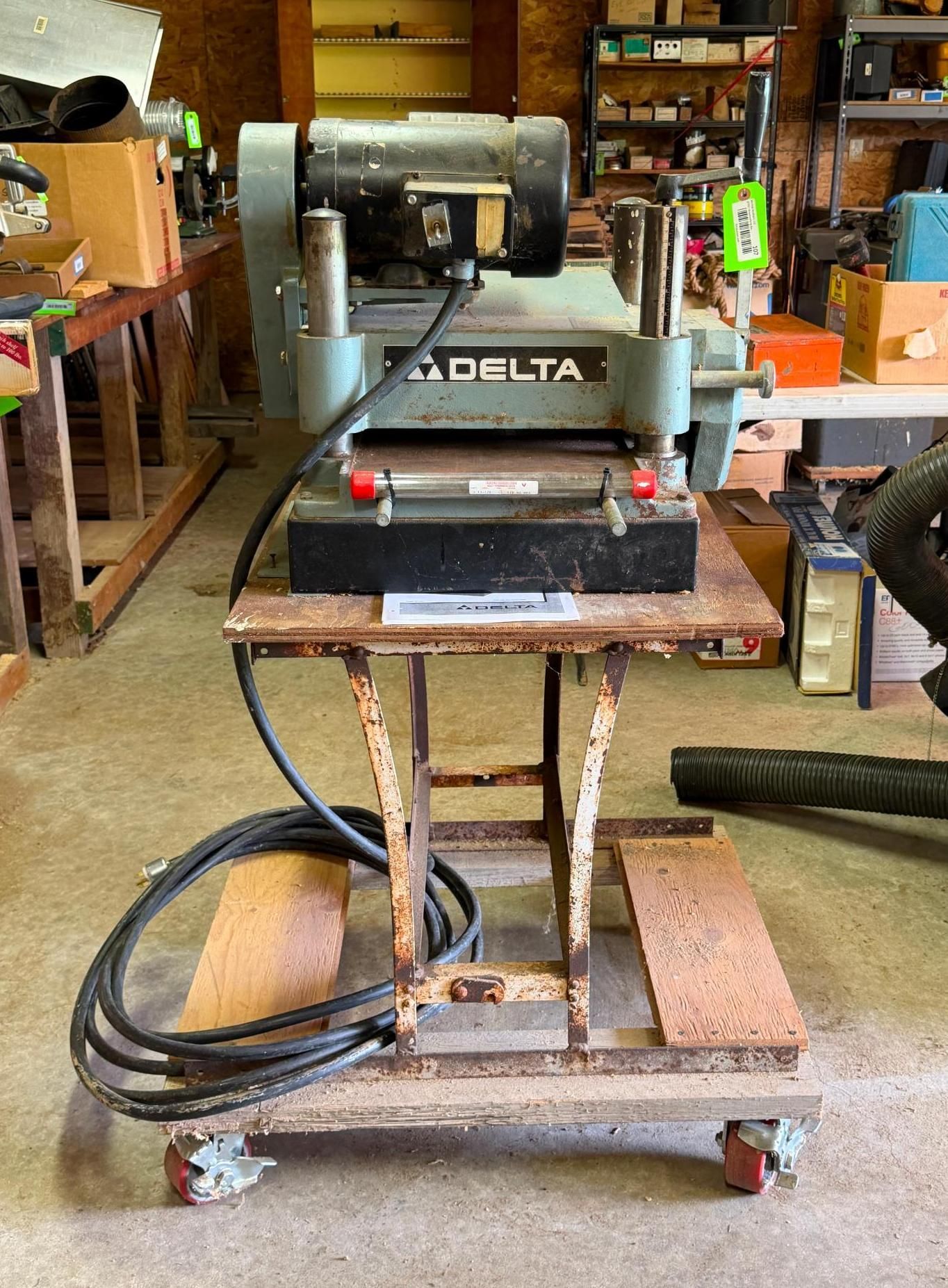 Delta benchtop thickness planer on a rolling wooden stand in a workshop garage.