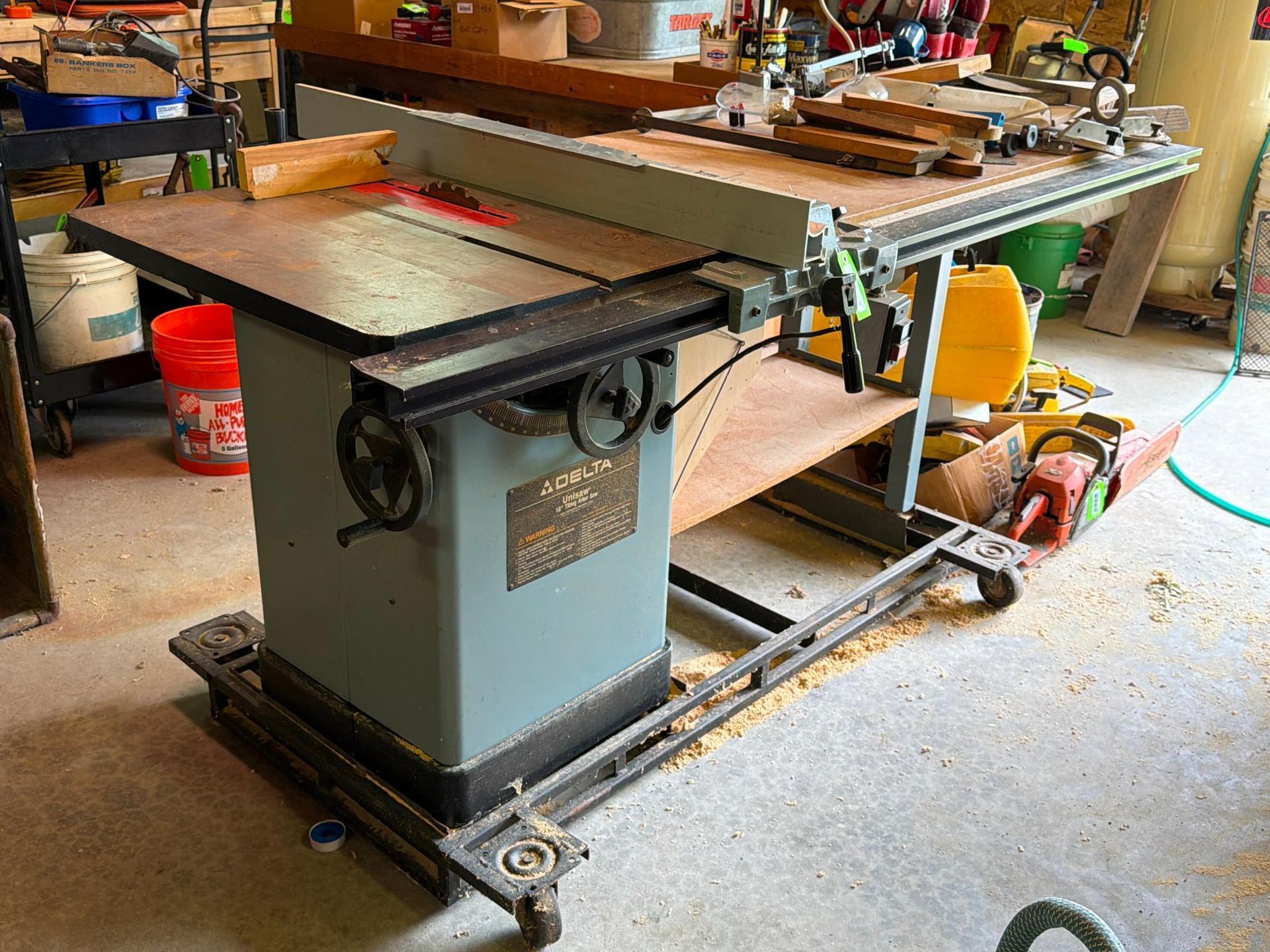 Table saw in a workshop, with a red extension table and dust collection hose.