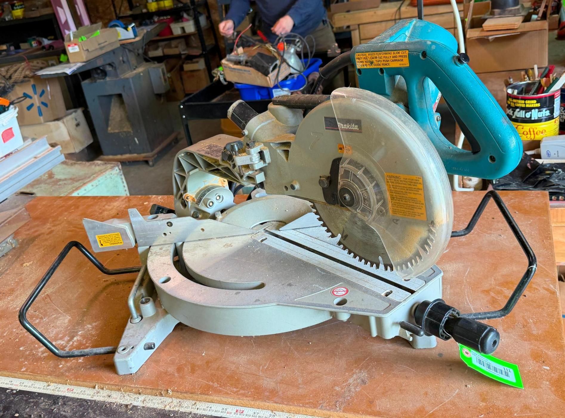 Miter saw on a workshop bench with a blue handle