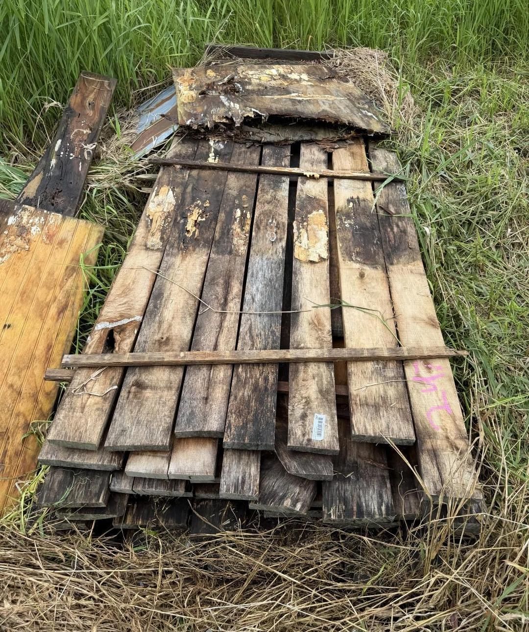 Stack of wooden planks tied together outdoors in grass