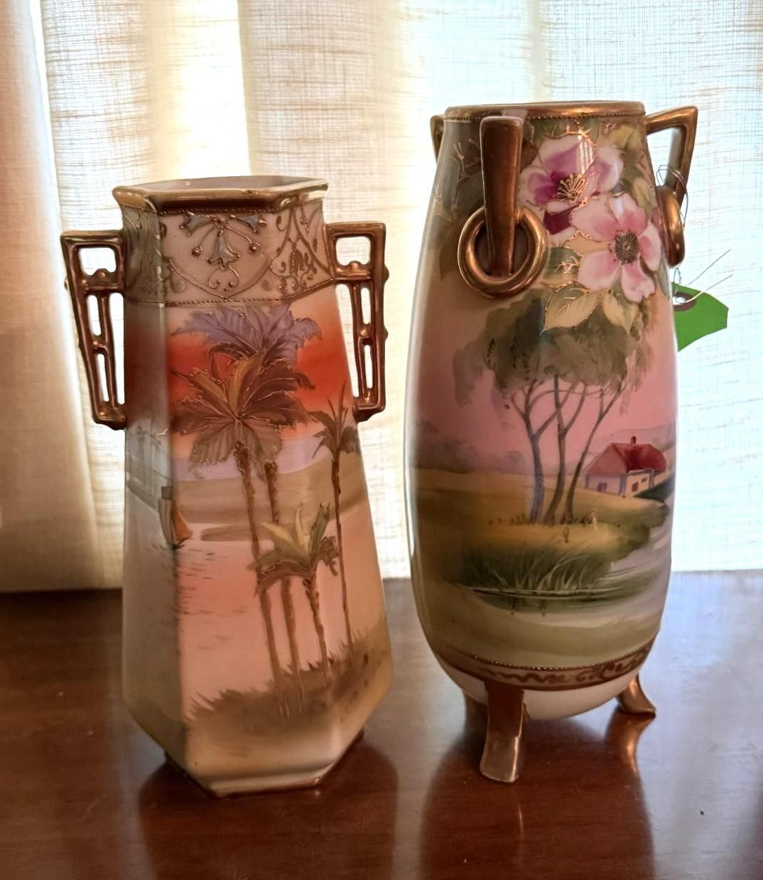 Two painted ceramic vases with floral designs on a wooden table