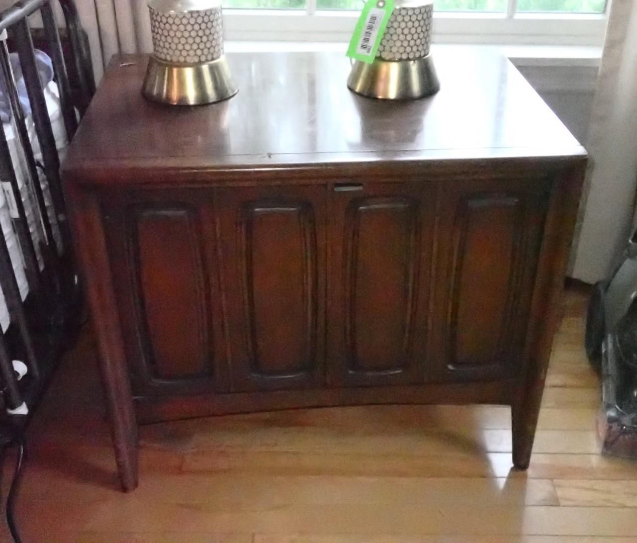 Dark wooden sideboard with two metal lamps on top beside a window