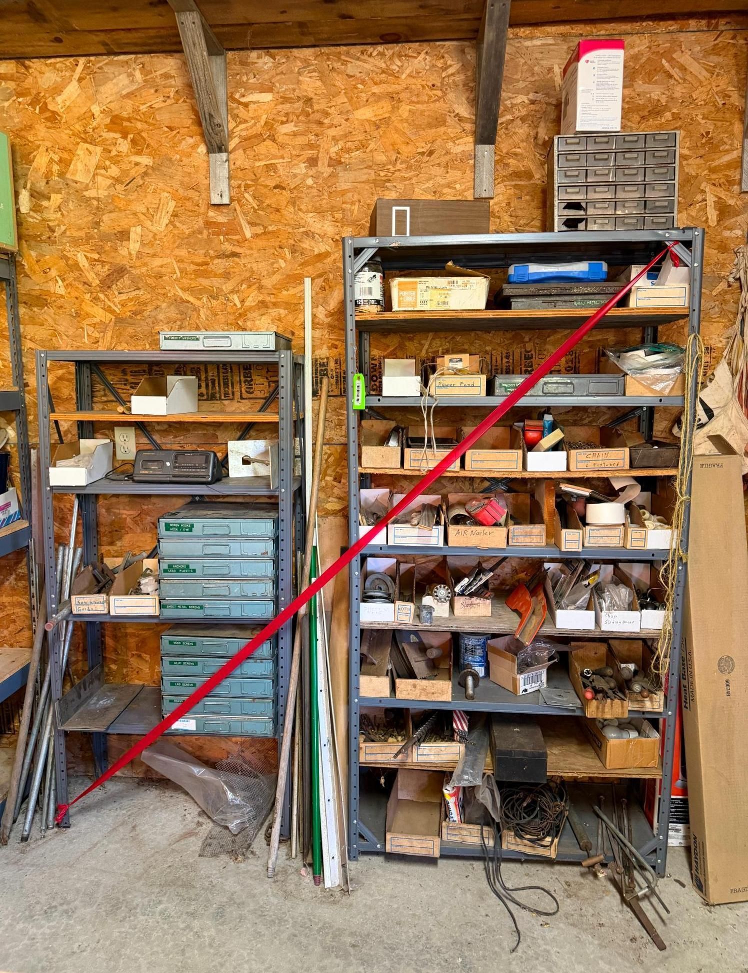 Workshop shelves packed with tools and boxes, with a red pole leaning diagonally