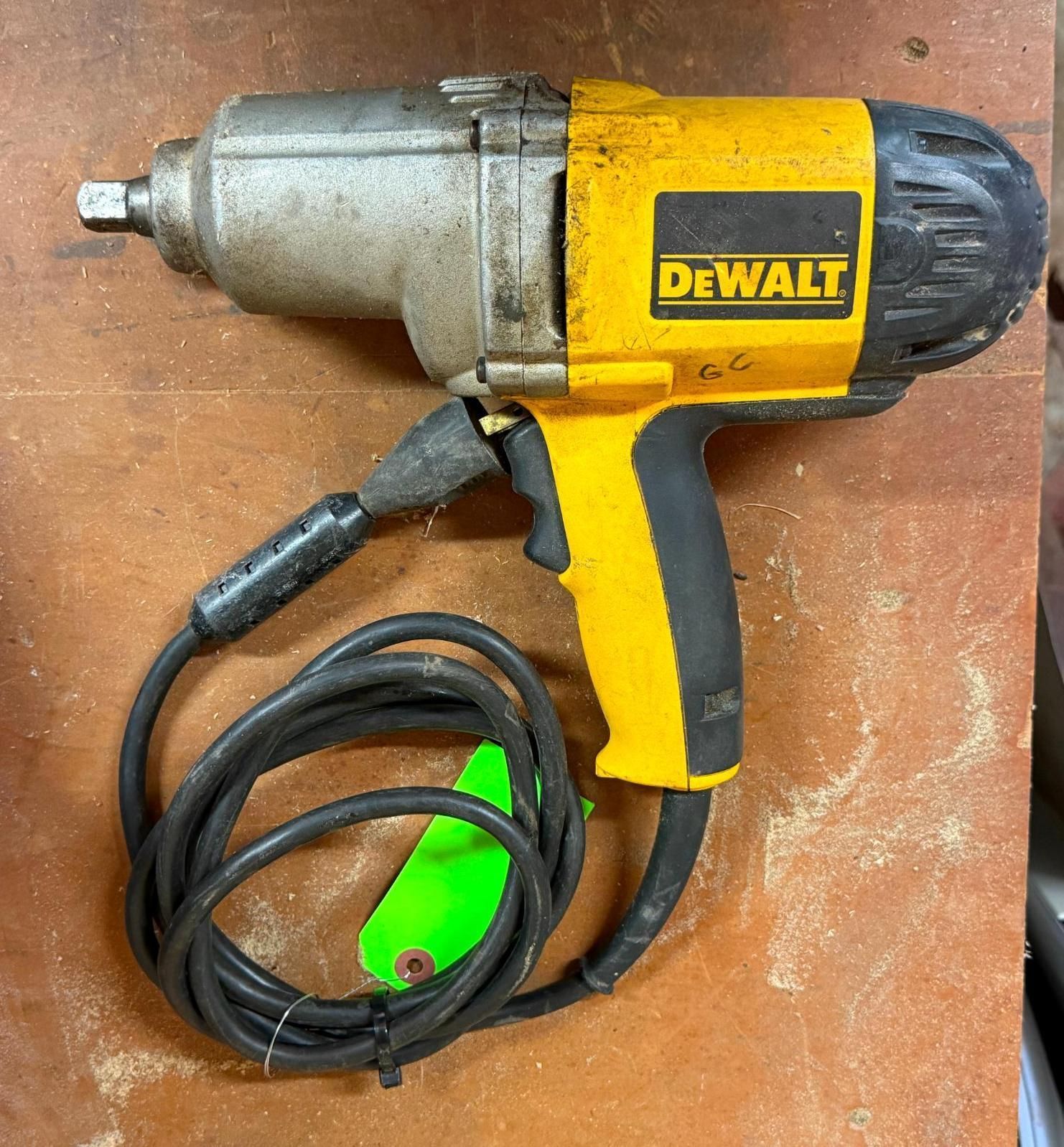Yellow and black DEWALT electric impact wrench with cord on a brown workbench
