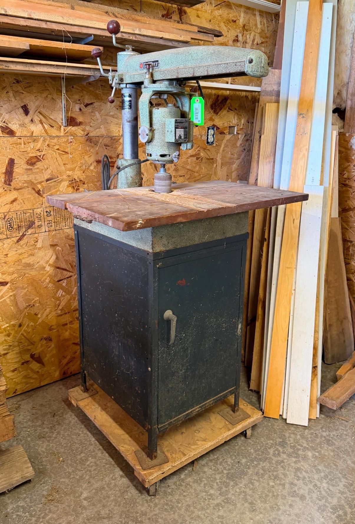 floor-standing drill press with a wooden worktable in a workshop