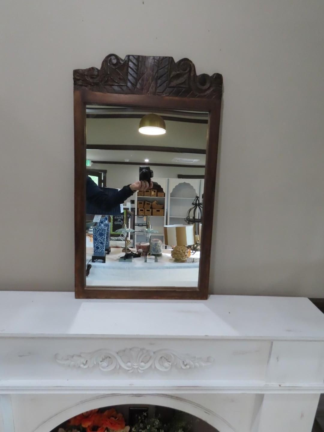 Small ornate wooden mirror on a white mantel