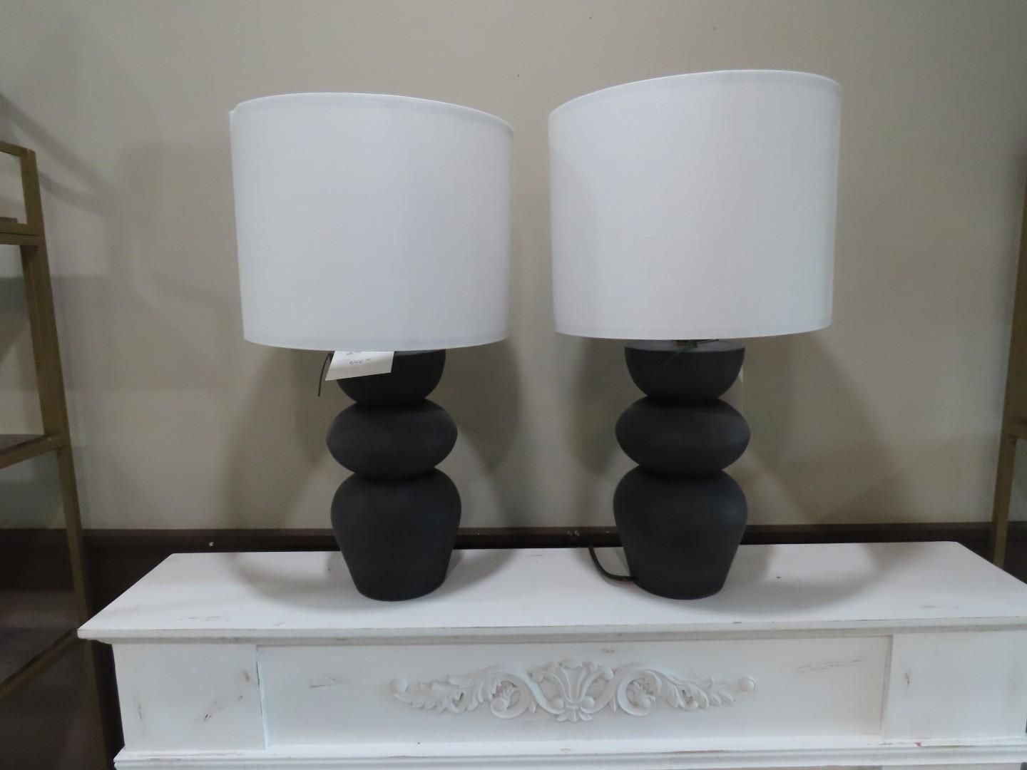 Two black-and-white table lamps on a white dresser against a beige wall.