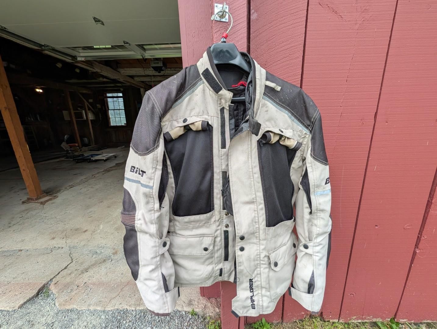 Hanging white and black motorcycle jacket outside a red building, seen front-on