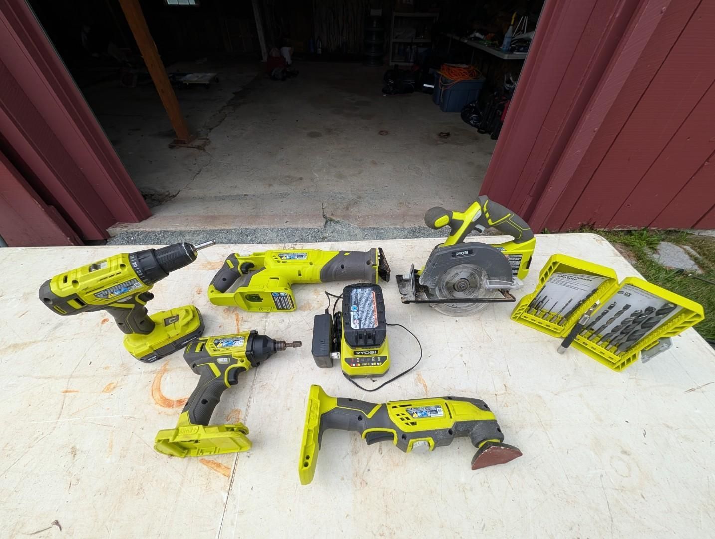 Yellow and black power tools and saw blades laid out on a white surface at a garage entrance