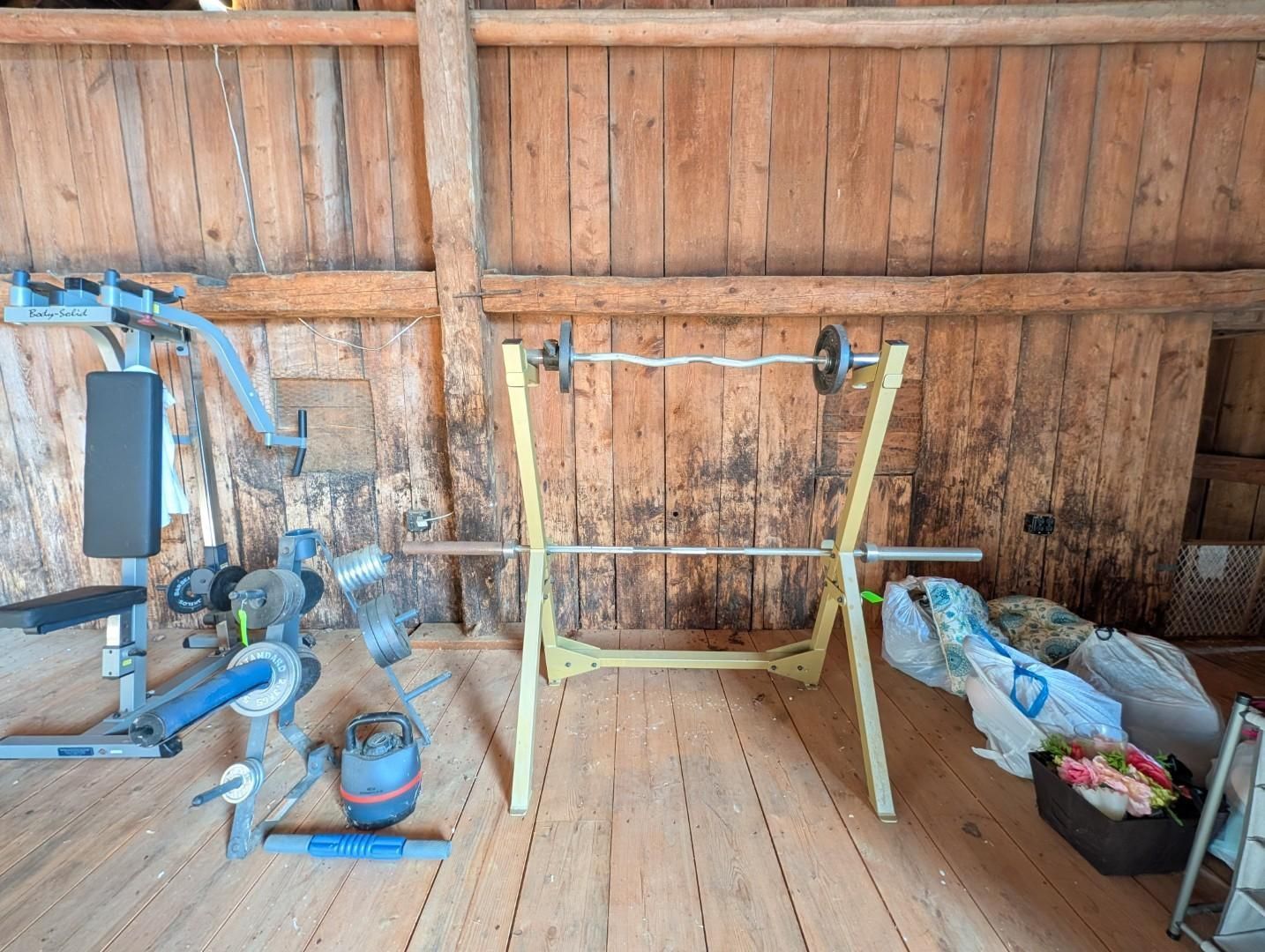 Workshop with a  industrial machine, a yellow stand, and tools against a wooden wall.