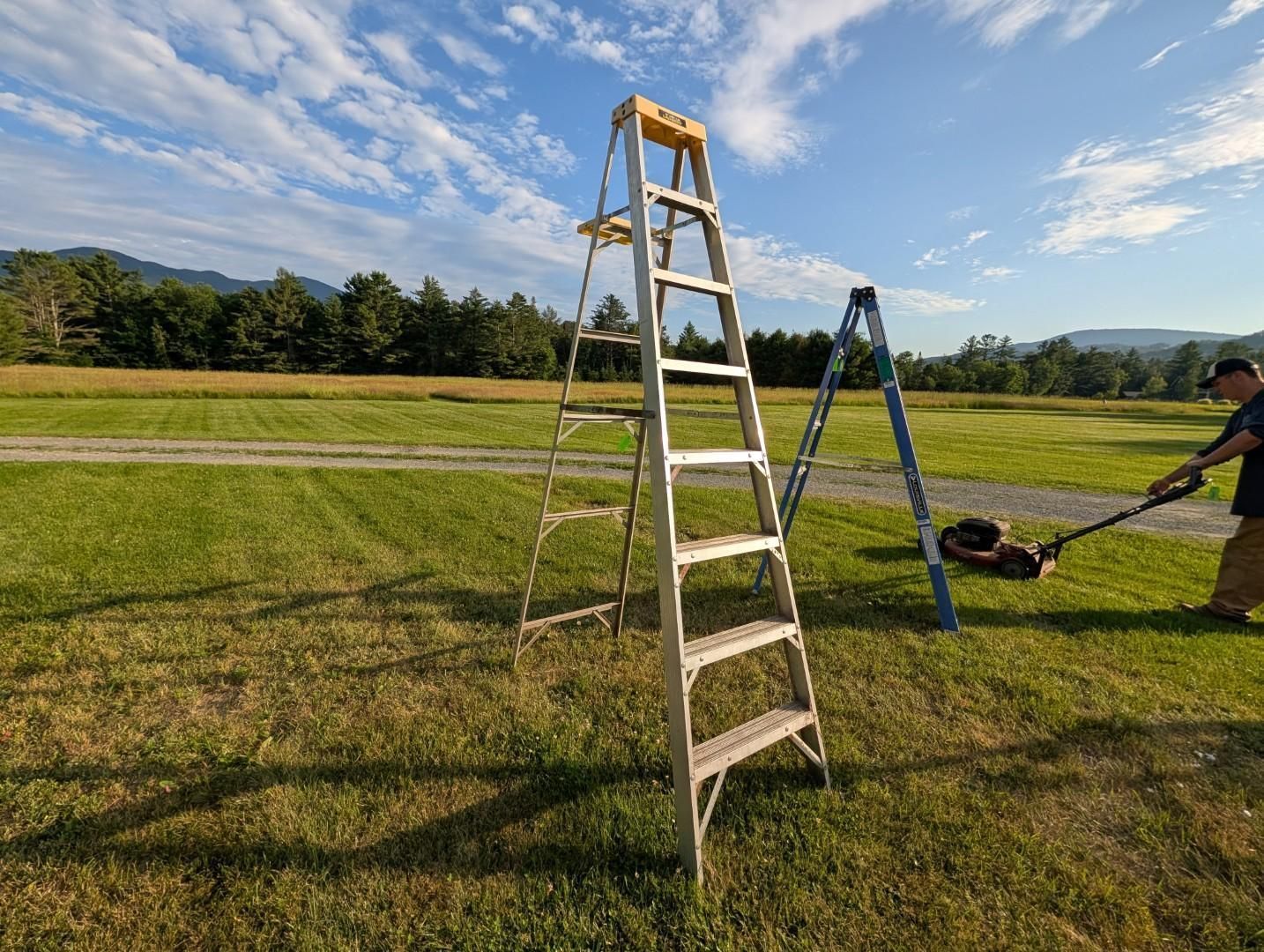 Ladder on a grassy field beside a blue A-frame