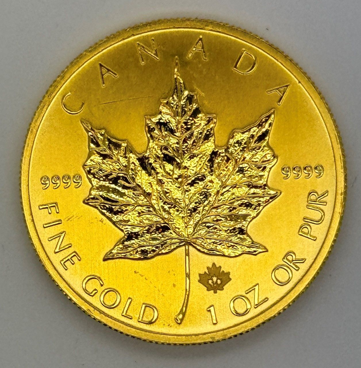 Canadian gold coin with maple leaf, labeled “CANADA” and “FINE GOLD 1 OZ OR PUR”