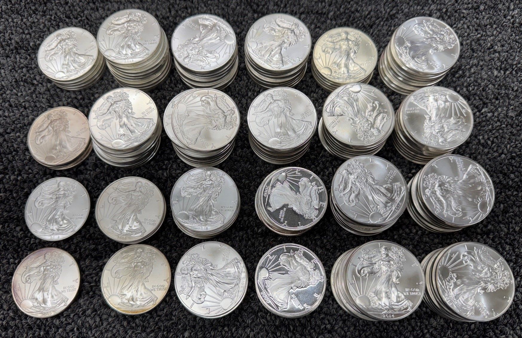 Neatly stacked rows of silver coins on a dark textured surface.