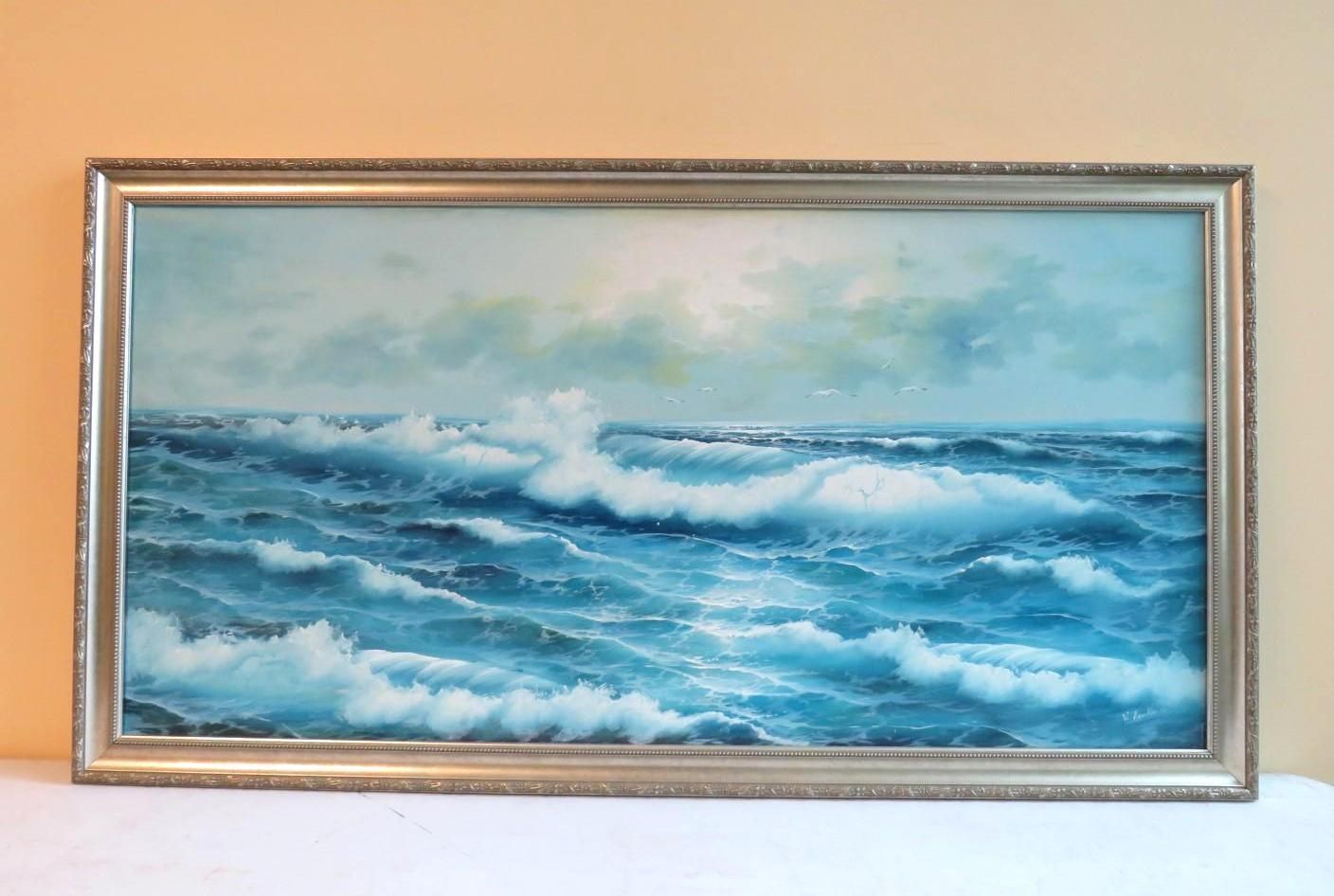 Oil painting of ocean waves breaking, in a silver ornate frame. Blue and white colors dominate, with clouds above.