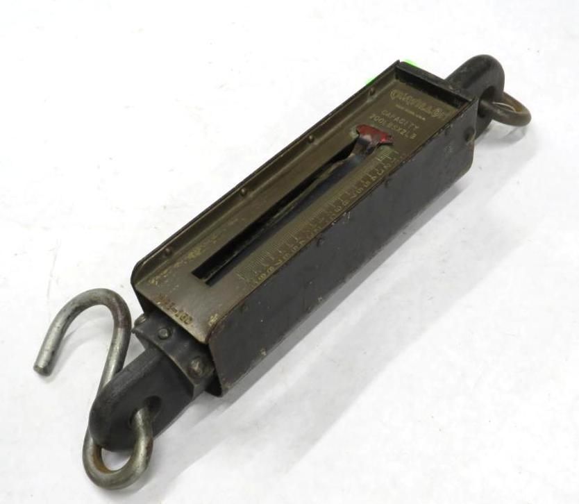 Black hanging scale with hooks. Displays a weight measurement.