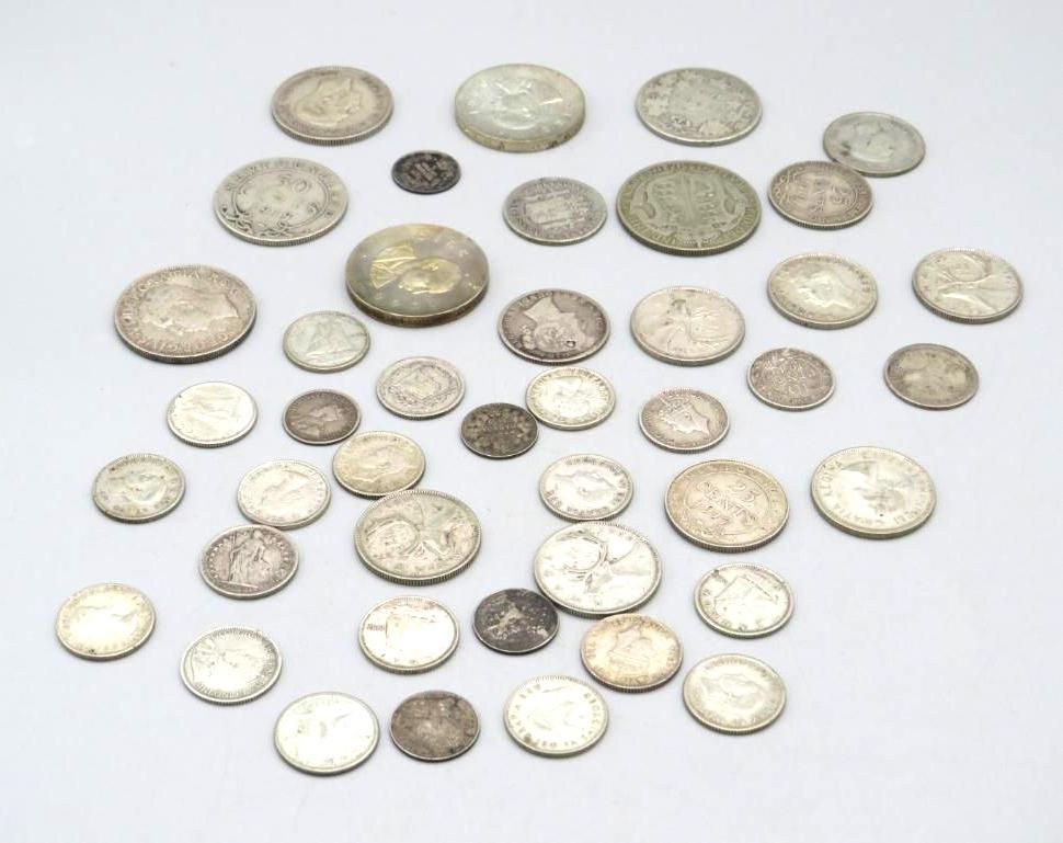 Scattered pile of silver coins on a white surface.
