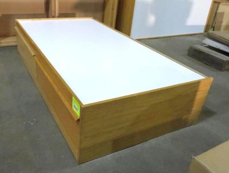Wooden platform bed with white top, indoors.