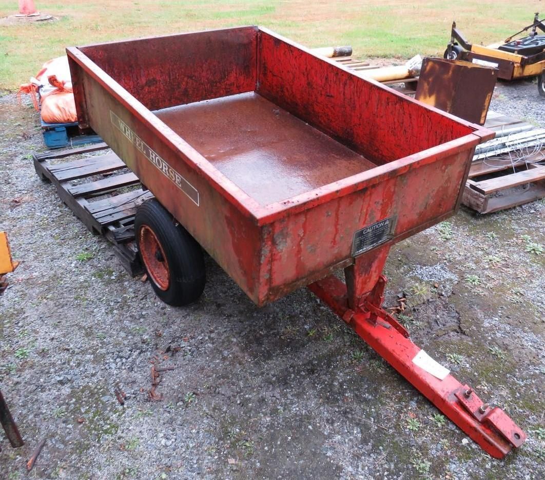 Red utility trailer with a rectangular bed, one tire, and a hitch. Outdoors.