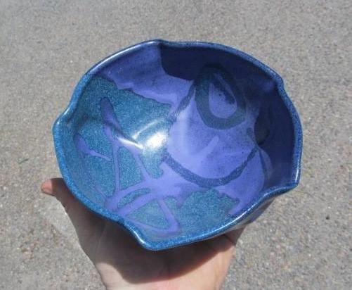 Hand holding a blue and teal ceramic bowl with abstract patterns.