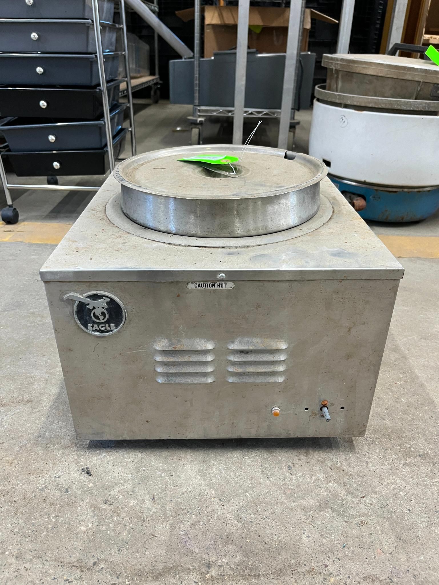 Stainless steel commercial food warmer.  Silver, with a circular top and vent-like openings on the front.
