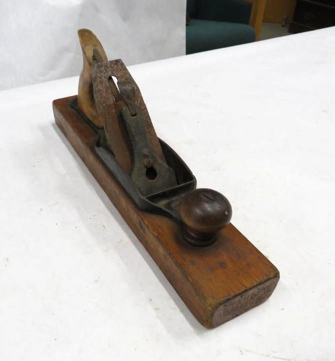 Wooden hand plane on a white surface, with a metal blade and wooden handle.