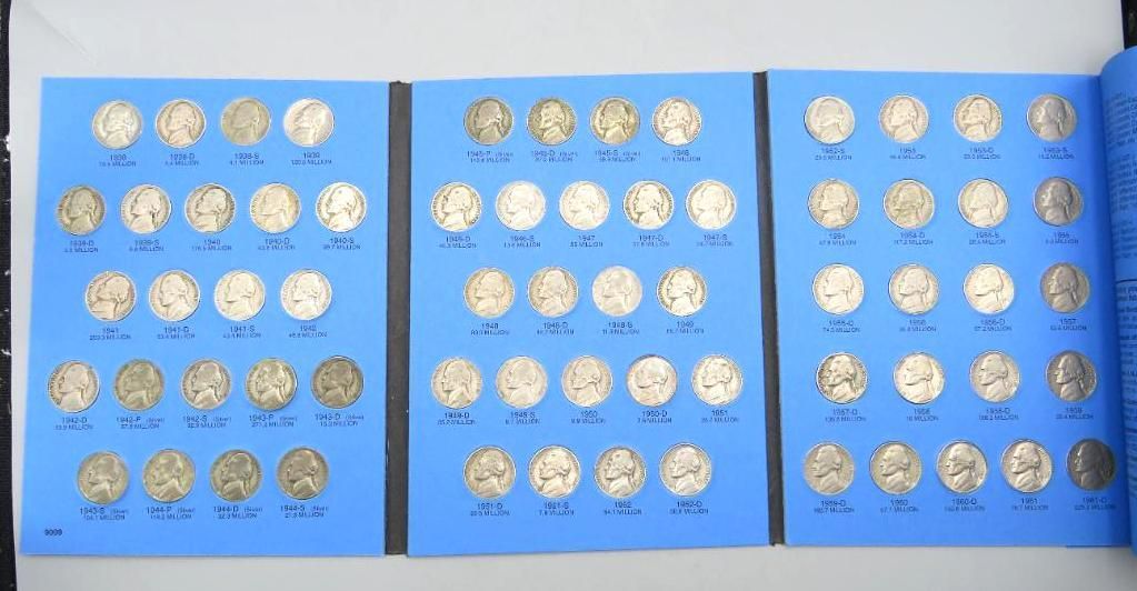 Three open coin collecting books filled with silver coins on blue pages.