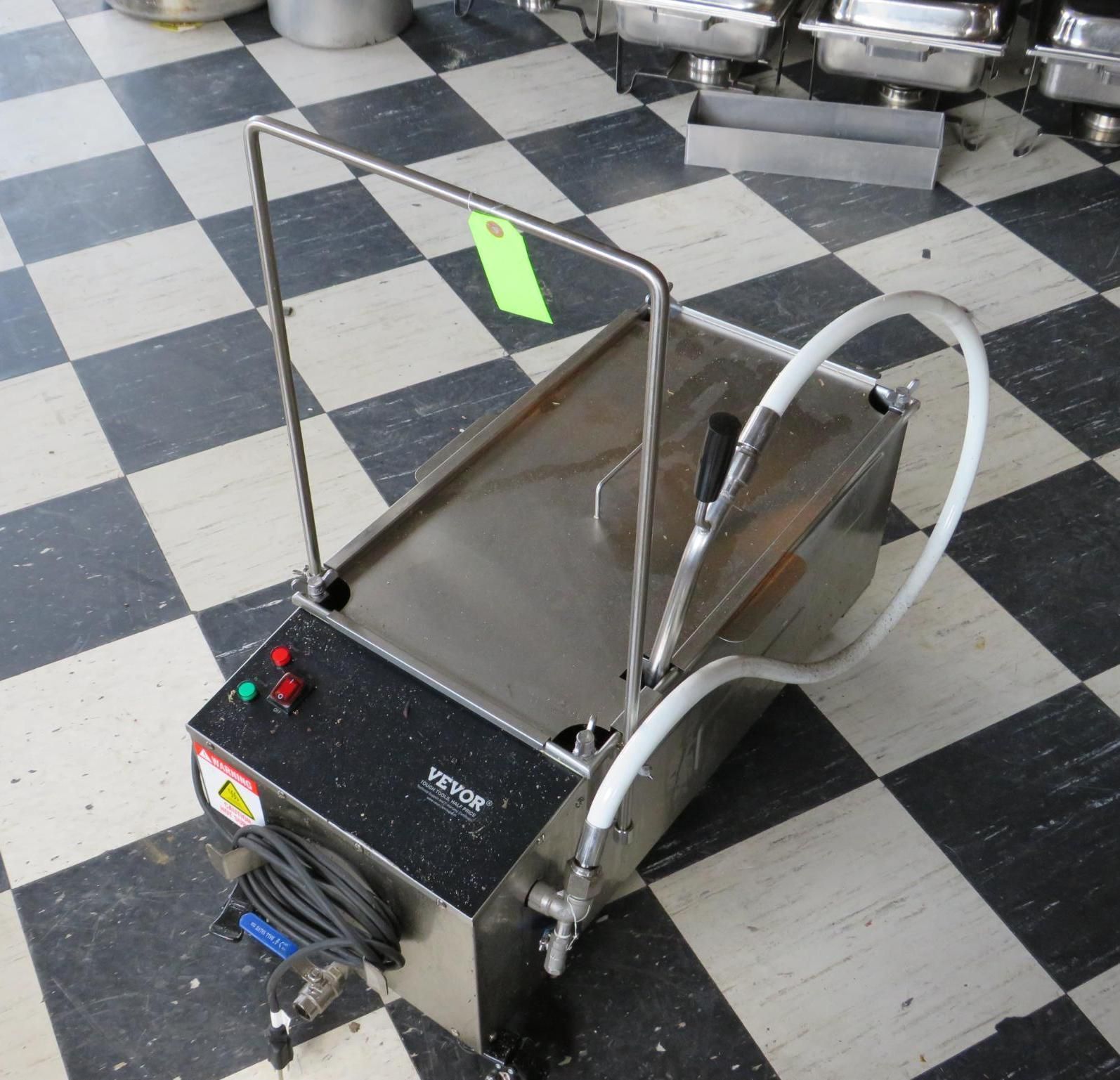 Stainless steel restaurant grease disposal machine on checkered floor.