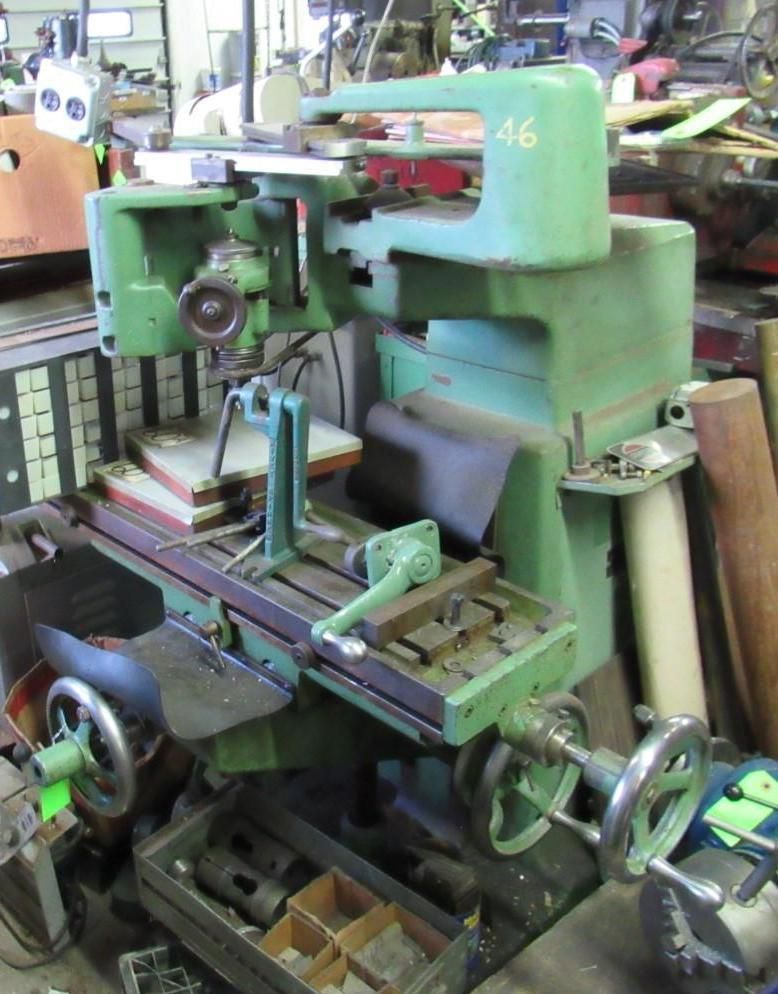 Green metal milling machine with several handles in a workshop.