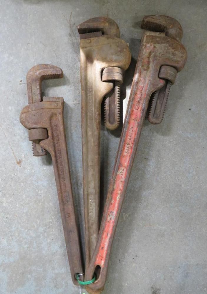 Three pipe wrenches on a gray surface.