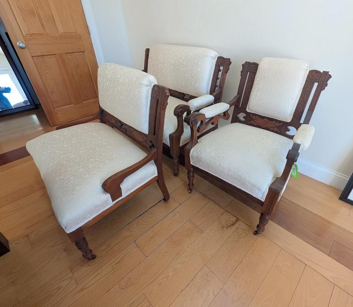 Two cream-upholstered wooden armchairs in a bright room on a light wood floor