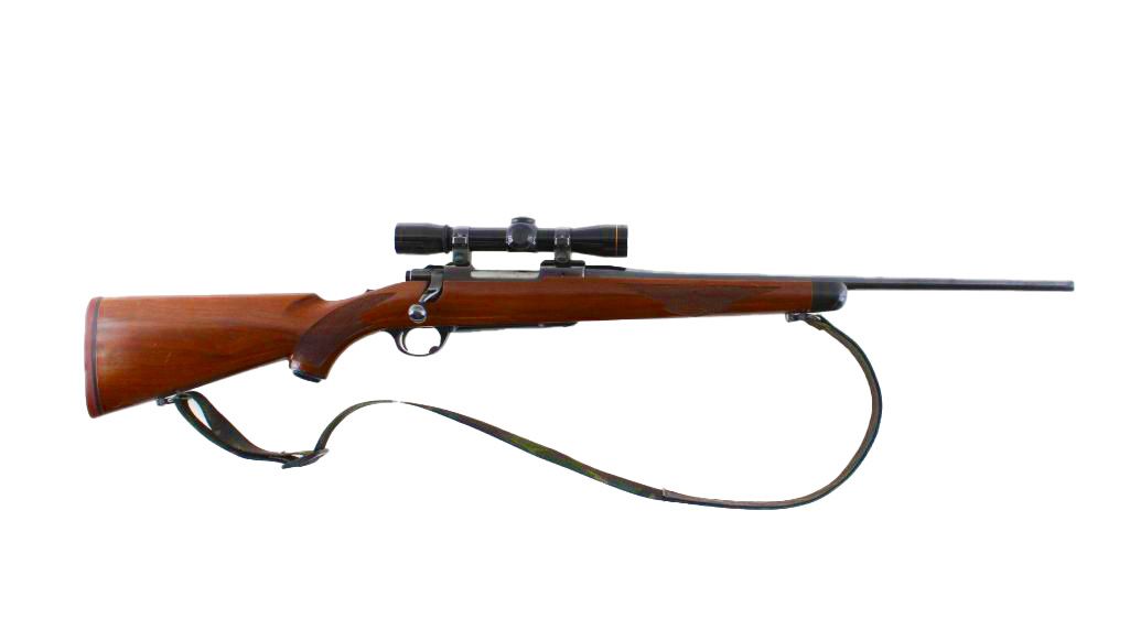 A bolt-action rifle with a scope and sling. It has a wooden stock.