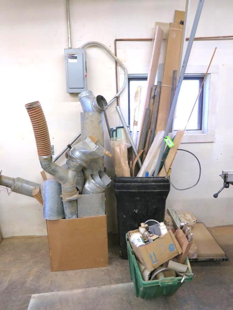 Wood scraps, metal ducts, electrical box, and buckets against a white wall with a window.