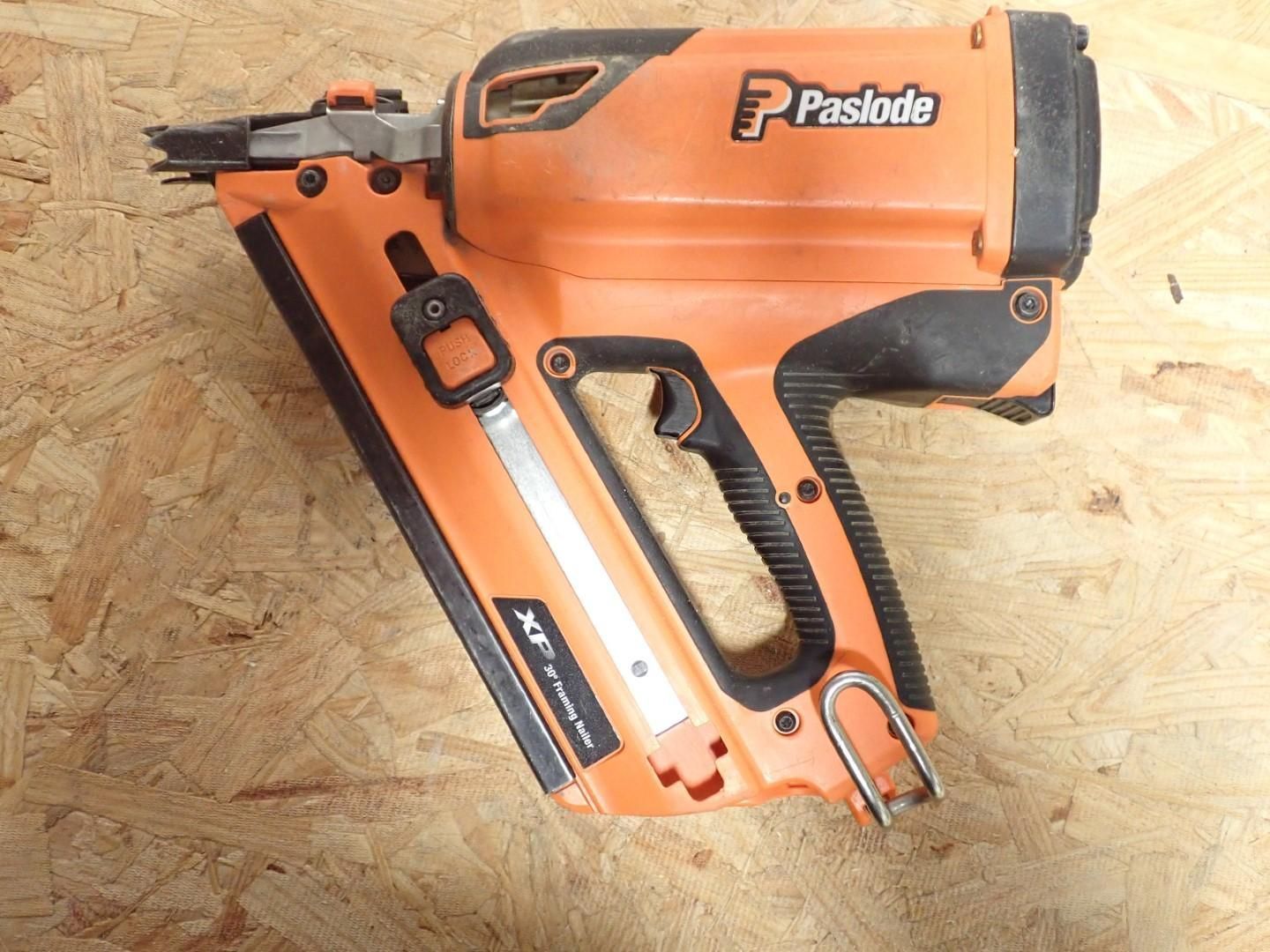 Orange Paslode cordless framing nailer, angled on wood.