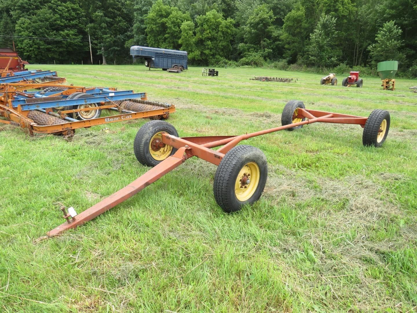 Brown farm trailer with yellow wheels on a grassy field.