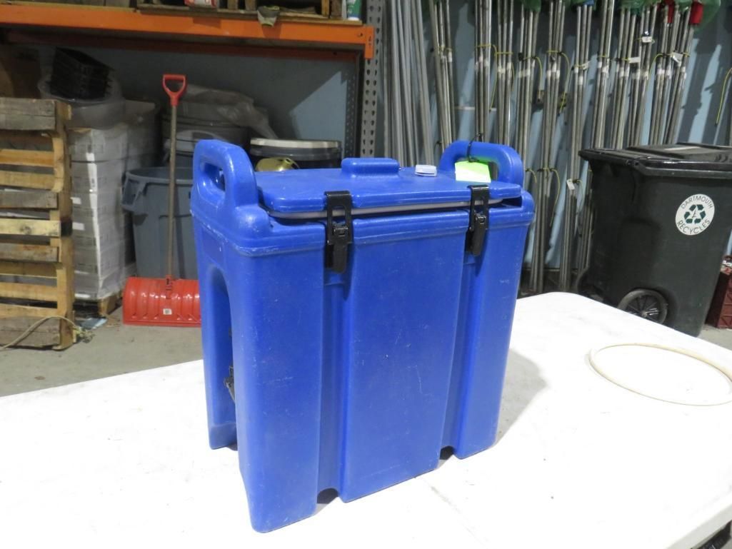 Blue insulated food carrier with latches, handles, and a closed lid, set on a white surface.