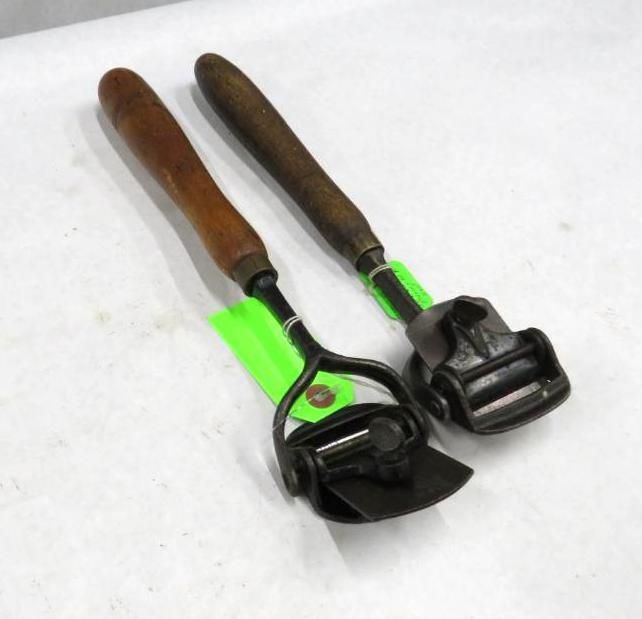 Two leatherworking tools with wooden handles and metal heads.
