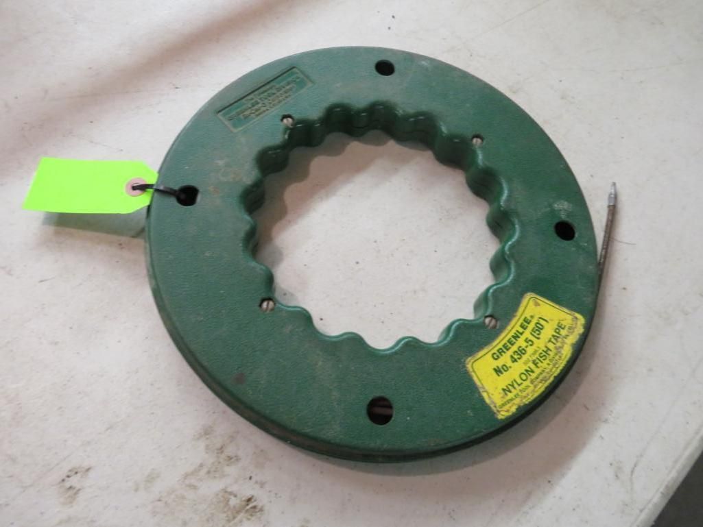 Green fiberglass fish tape reel with a yellow label and a green tag on a light-colored surface.