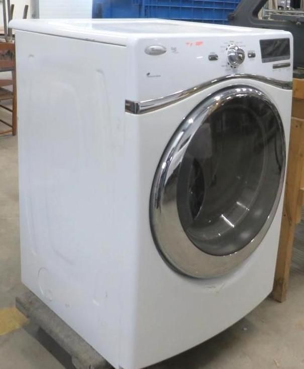 White Whirlpool front-load washing machine with chrome accents, sitting on a wooden pallet.