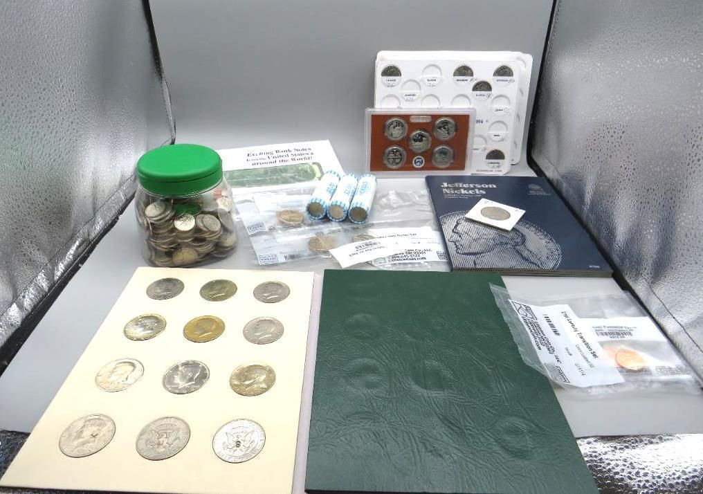 Collection of coins, including a jar, rolls, coin holders, and albums, arranged on a surface.