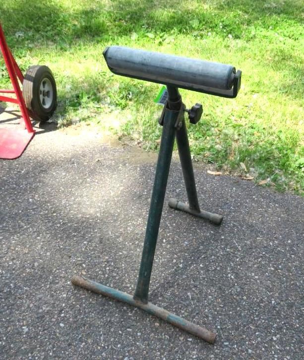 Green roller stand on asphalt, likely for supporting materials.