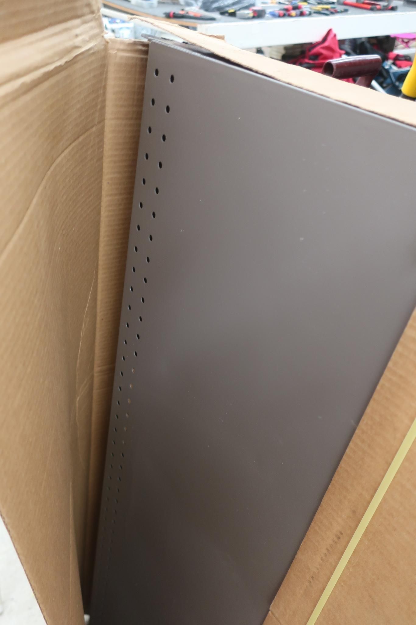 Brown metal panel in a cardboard box, with holes along one edge.