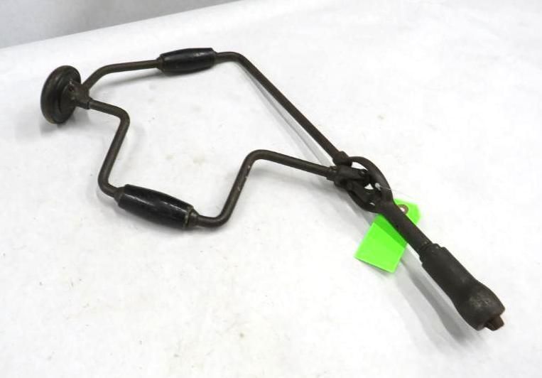 Hand-powered brace and bit drill with black wooden handles, on a white surface.