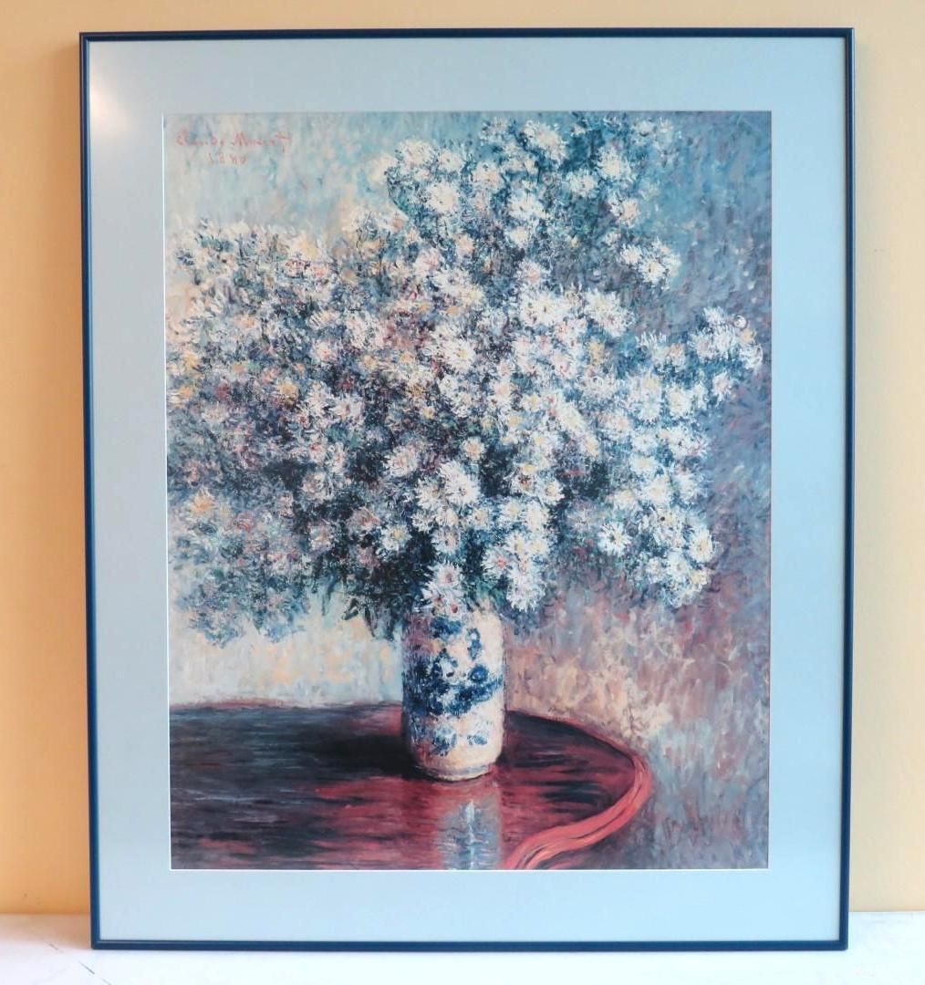 Still life of white flowers in a vase on a red table, framed.