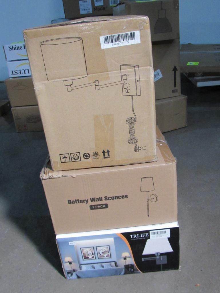 Three cardboard boxes stacked, a battery wall sconce box is visible at the bottom.