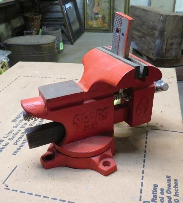 Red Sears bench vise on a cardboard surface.